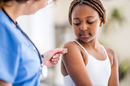 A provider putting a bandage on a girl's arm